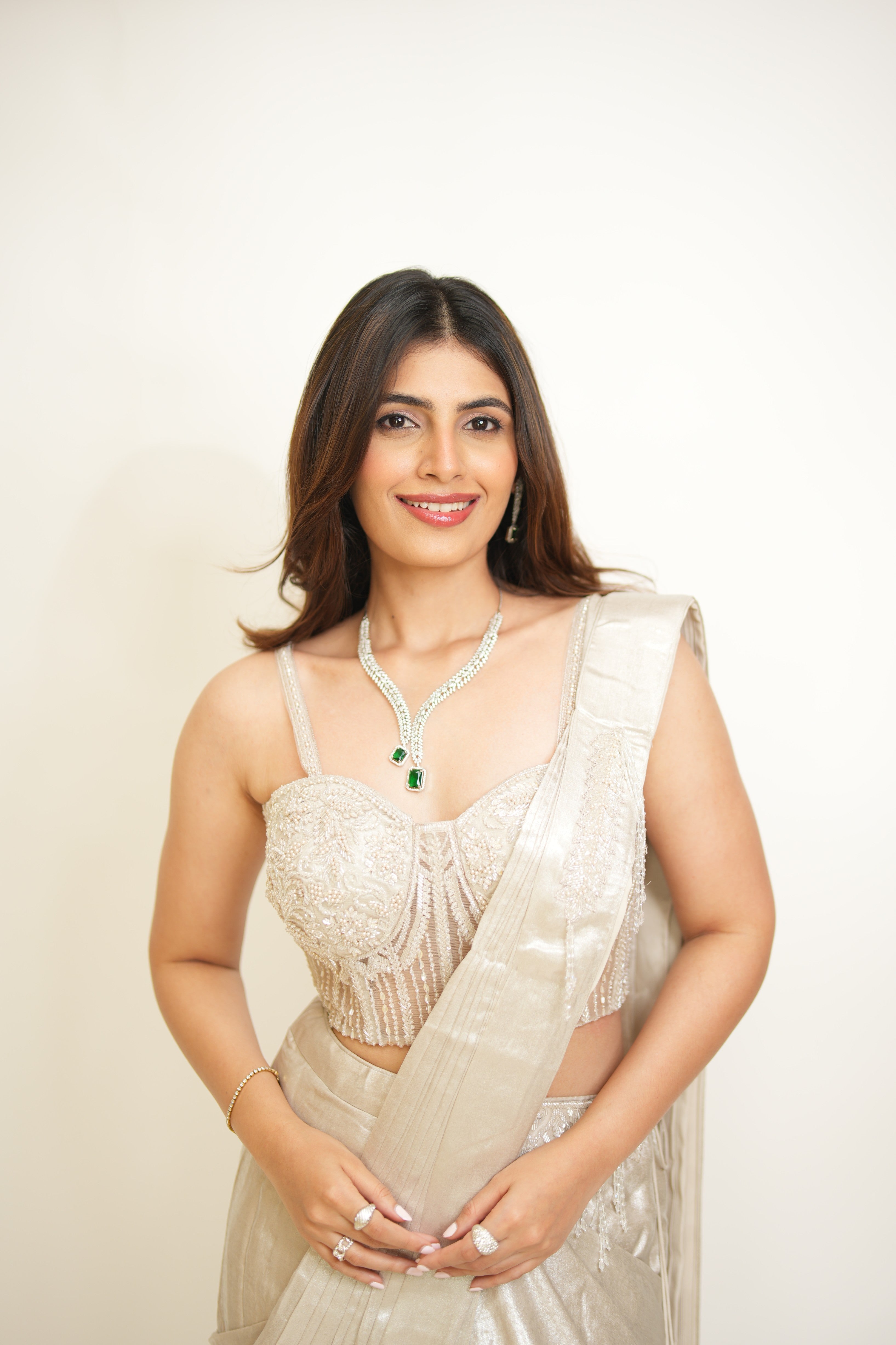 Woman wearing a beige saree with a plain background