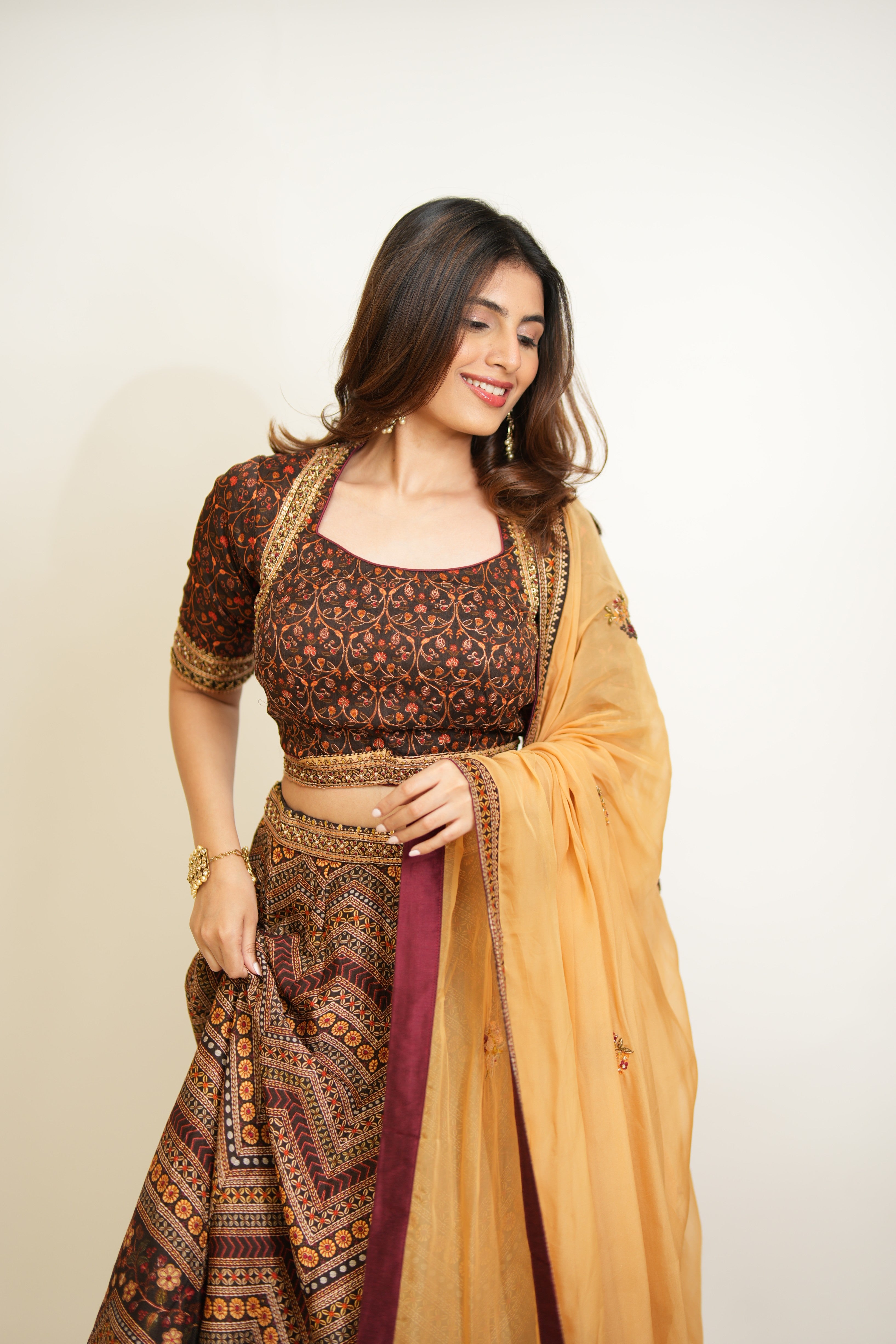 Woman wearing a traditional outfit with a patterned blouse and lehenga 
on a plain background
