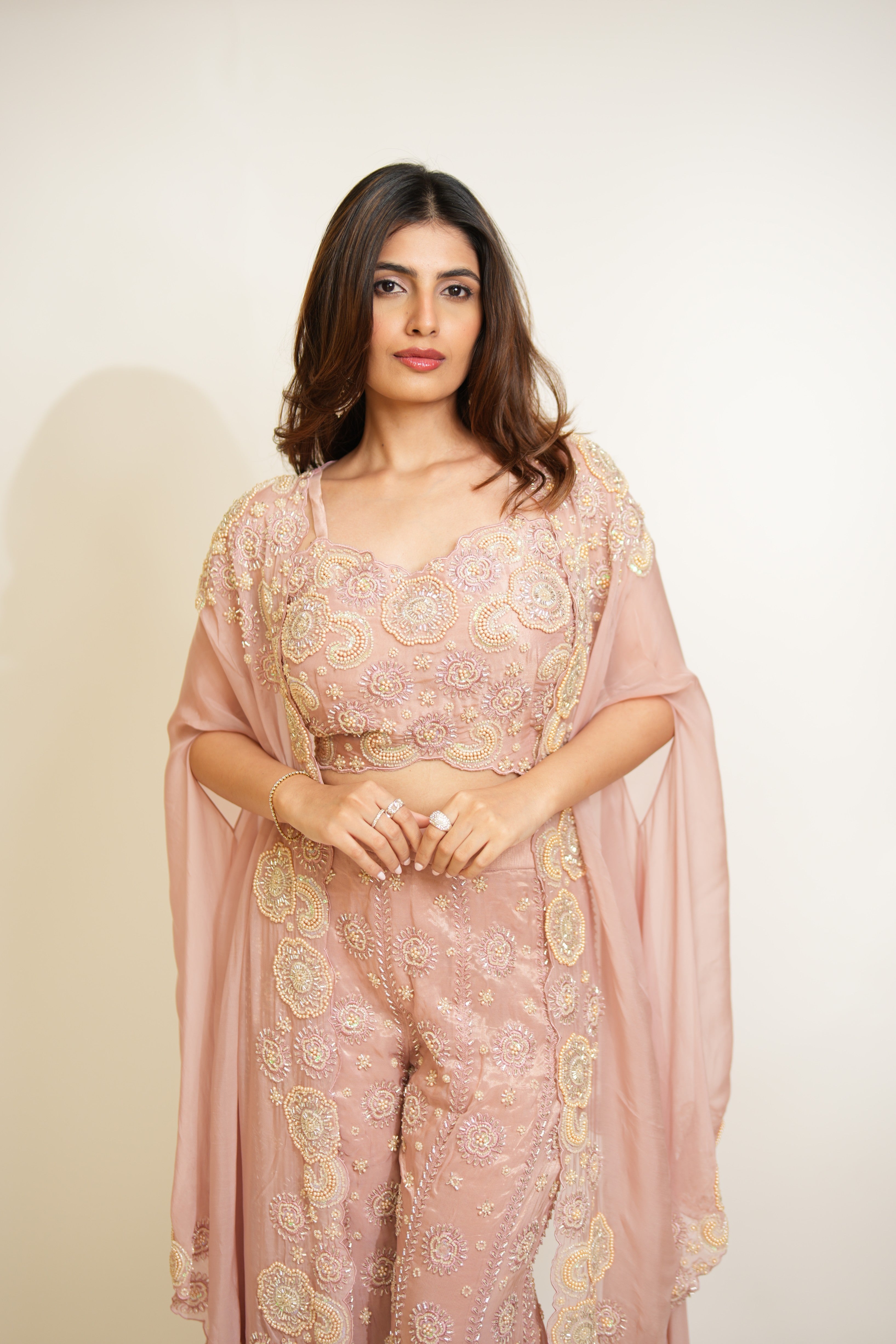 Woman wearing a pink traditional outfit with a sheer dupatta against a white background