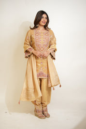 Woman wearing a traditional beige embroidered outfit on a white background