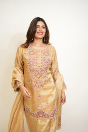 Woman wearing a beige embroidered traditional outfit on a white background