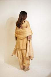 Woman wearing a traditional beige outfit with a shawl on a white background
