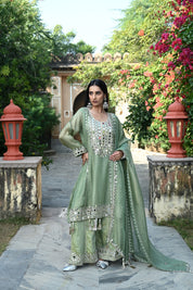 Sage-green traditional outfit featuring a mirror-embroidered kurta with wide sleeves, matching wide-legged trousers with embellished hems, and a coordinating dupatta finished with reflective detailing and tassels.