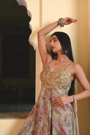 Model wearing a pastel floral printed Anarkali gown with an embroidered bustier and sheer jacket, styled with statement earrings and bangles, posing against a heritage archway for Tulsi Studio festive collection.