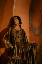 Woman in a traditional outfit standing against an orange wall with a horseshoe decoration.