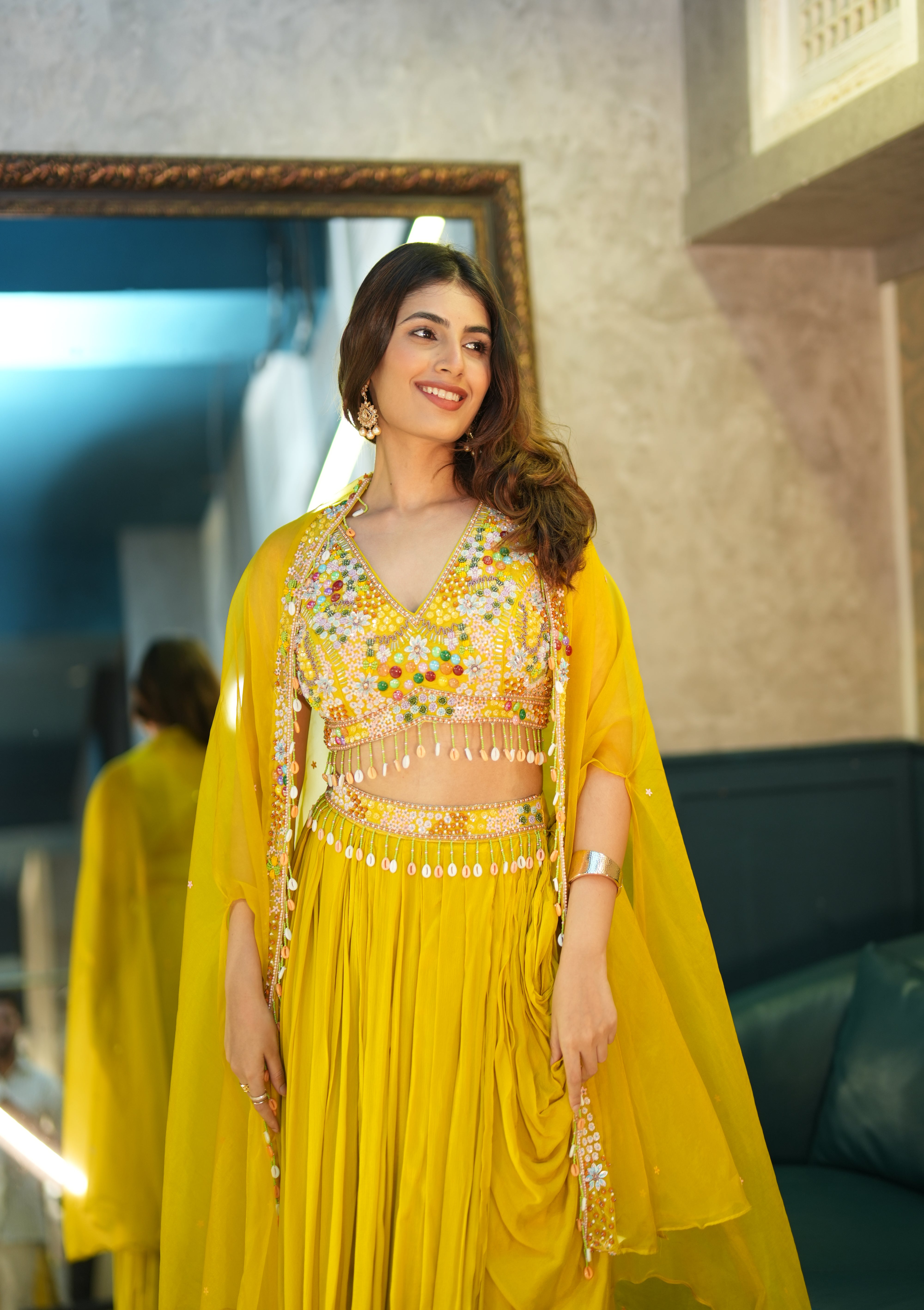 Woman in a yellow traditional outfit with floral patterns indoors.
