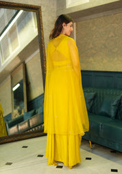 Woman in a yellow dress standing in a room with a mirror and green sofa.