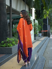 Woman in an orange and purple traditional outfit walking outdoors.