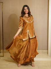 Woman wearing a mustard traditional outfit with gold embroidery in a room.
