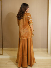 Woman wearing a traditional outfit with a mustard top and long skirt in a neutral setting