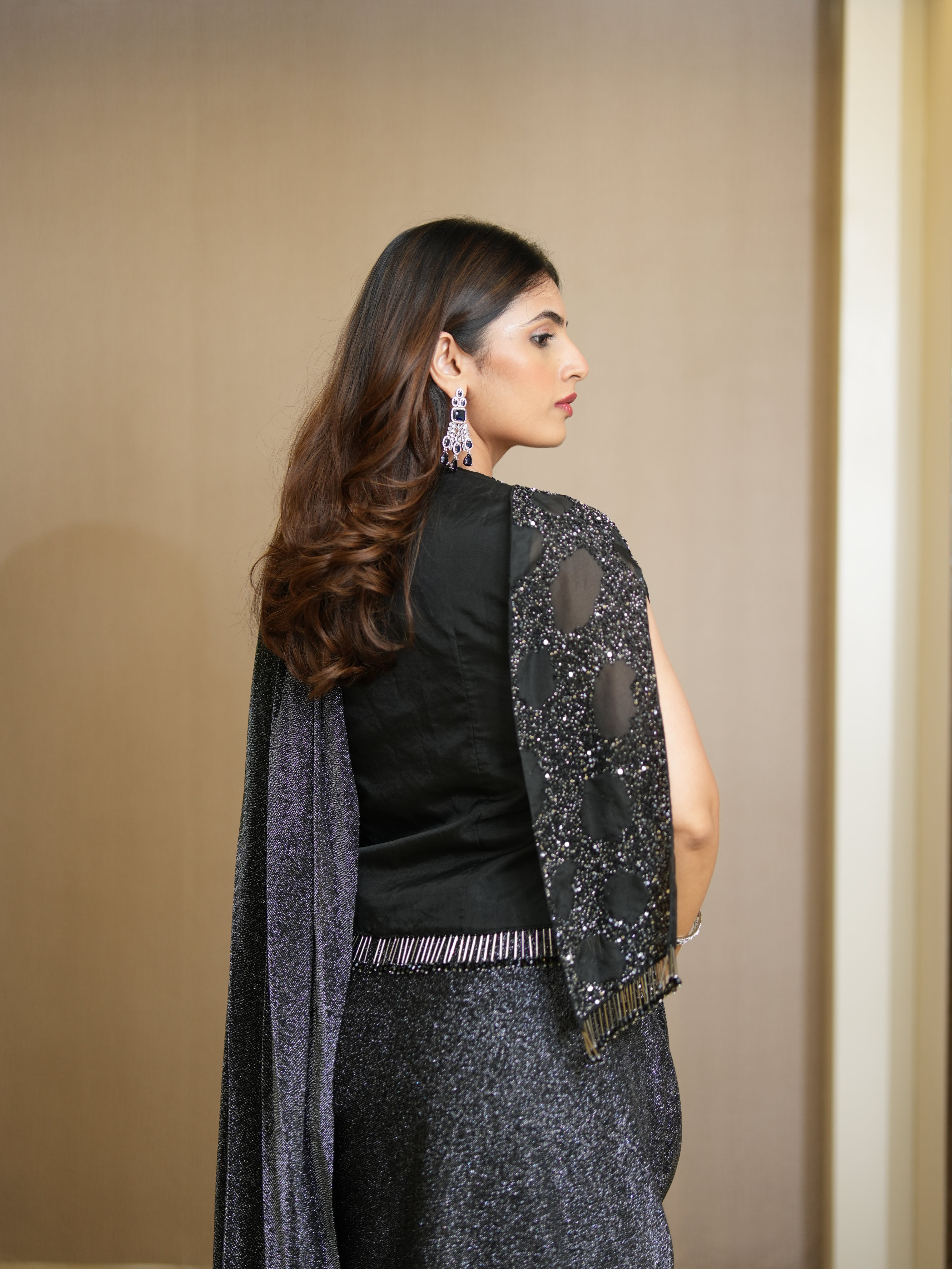 Woman wearing a black top and gray skirt with a matching shawl against a beige background