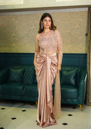 Woman in a pink drake skirt set standing in a room with green sofa and patterned wall.