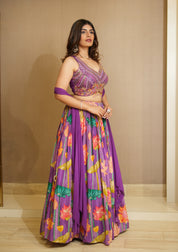 Woman wearing a purple floral outfit against a beige wall.