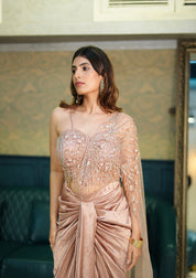 Woman in a pink drake skirt set with intricate designs standing indoors.