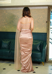 Woman in a pink drake skirt set standing in a room with green sofas and a patterned wall.