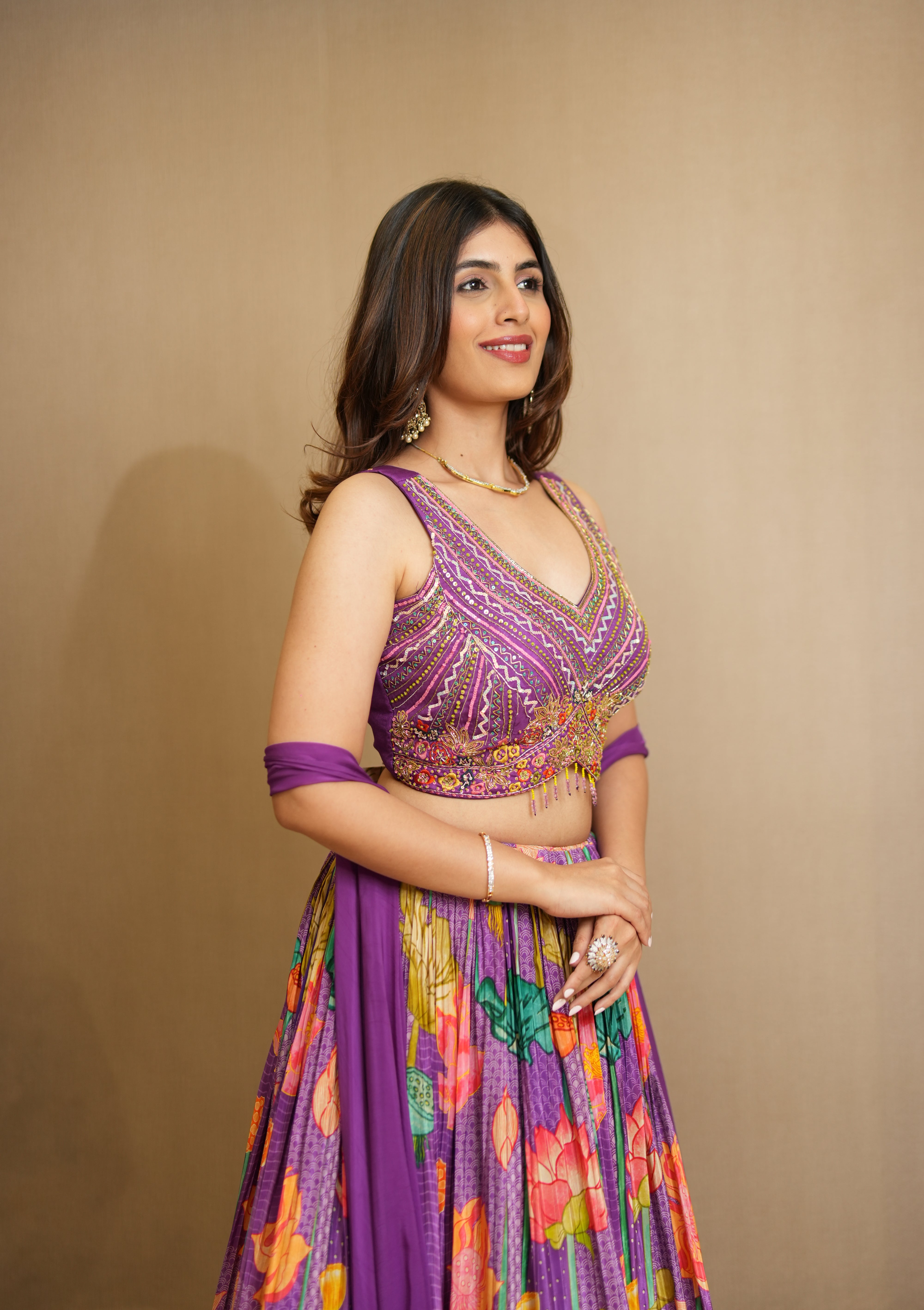 Woman wearing a colorful traditional outfit with a purple blouse against a beige background