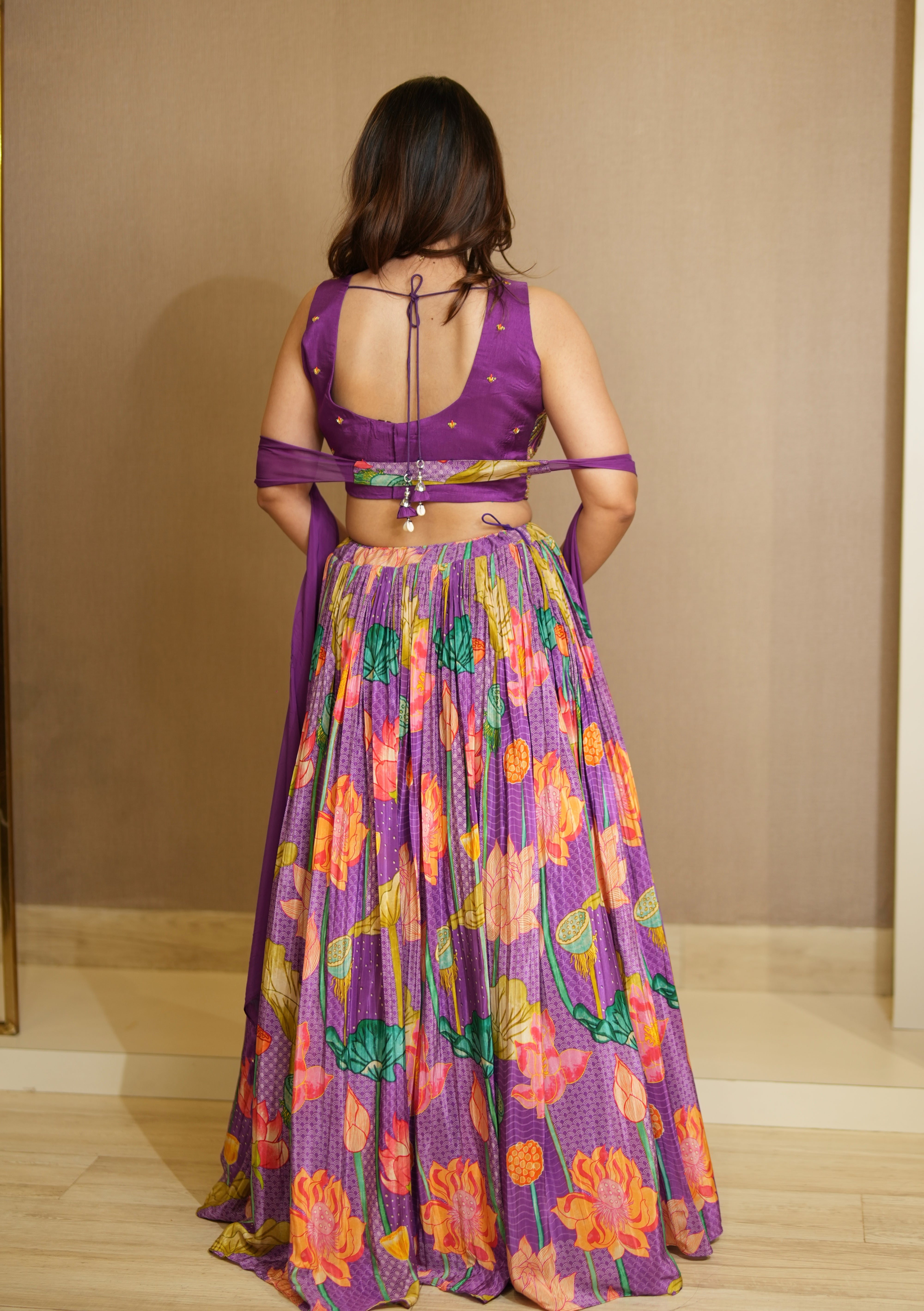 Woman wearing a vibrant purple floral dress with a plain background