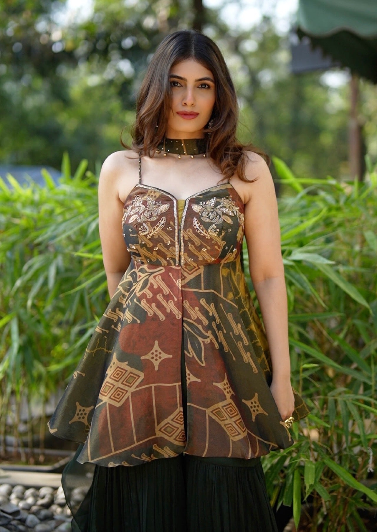 Woman wearing a patterned top with a blurred green outdoor background