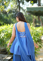 Woman in a blue dress walking outdoors with greenery in the background